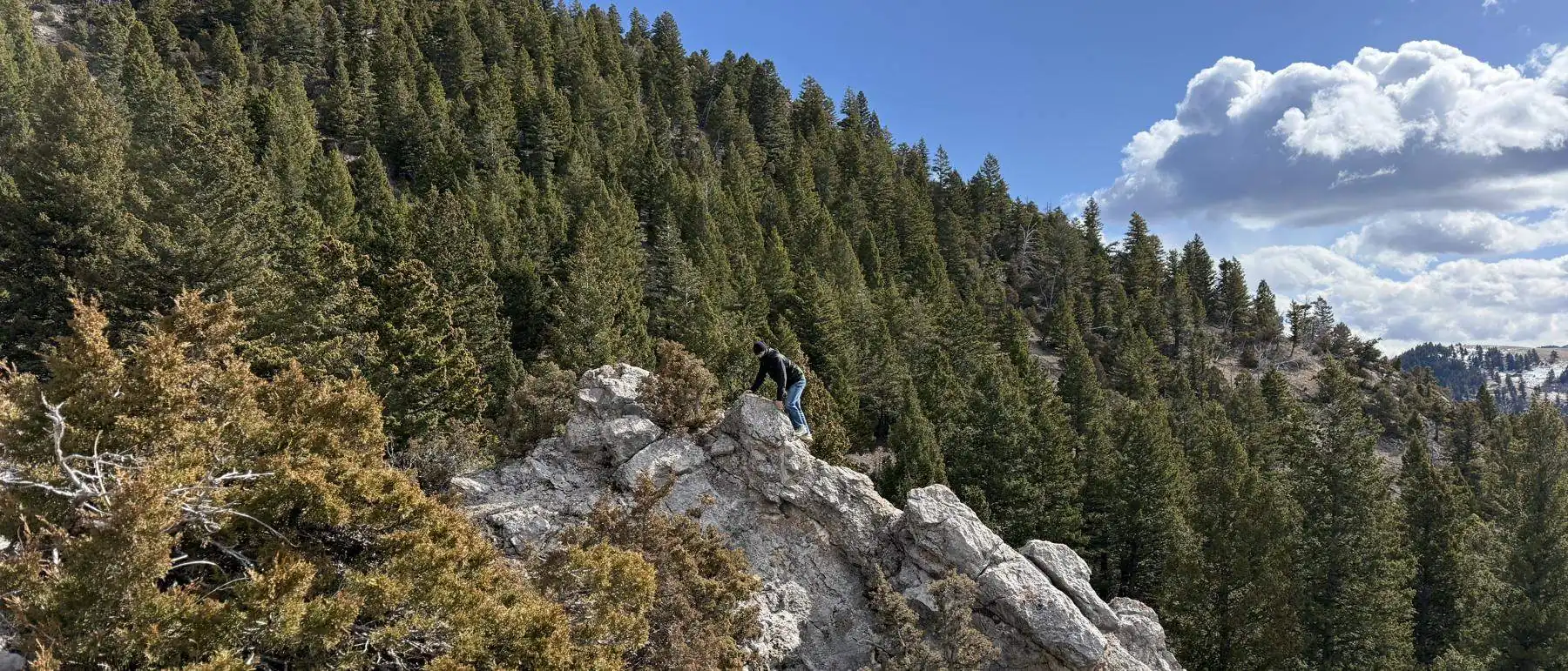 Charlie standing on a rock outcrop above a wide mountain valley